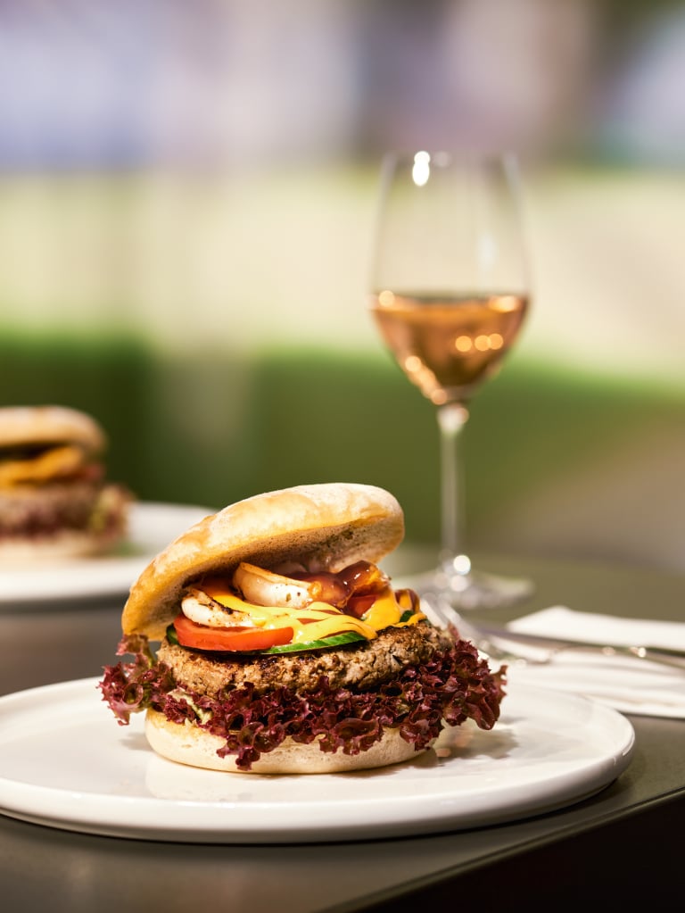 Burger auf einem weißen Teller und ein Weinglas