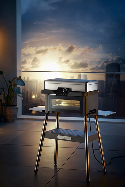 Urban Master Grill steht auf einem Balkon mit bläulichem Himmel