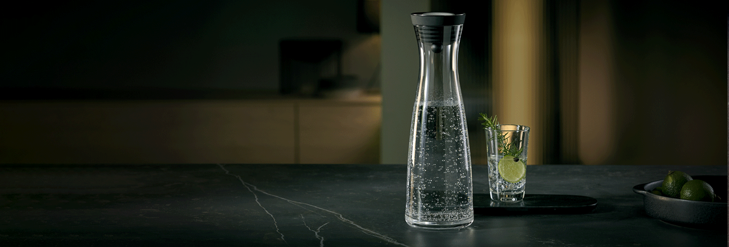 Mit Wasser gefühlte Wasserkaraffe Basic und ein Wasserglas mit Limette und Kräuter