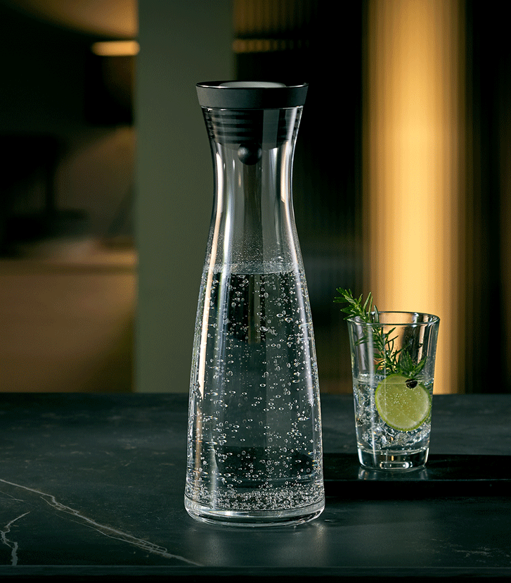 Mit Wasser gefühlte Wasserkaraffe Basic und ein Wasserglas mit Limette und Kräuter