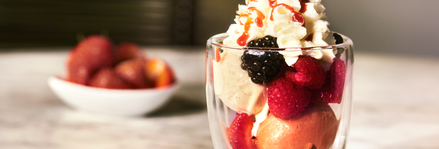 Glas mit Eis, Beeren und Schlagsahne